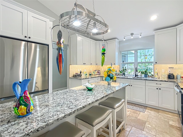 kitchen featuring freestanding refrigerator, white cabinetry, and stone tile floors