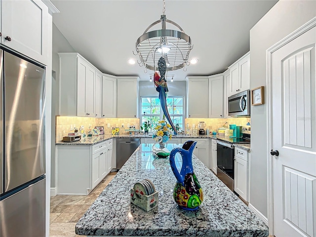 kitchen featuring stainless steel appliances, light stone counters, decorative backsplash, and white cabinets