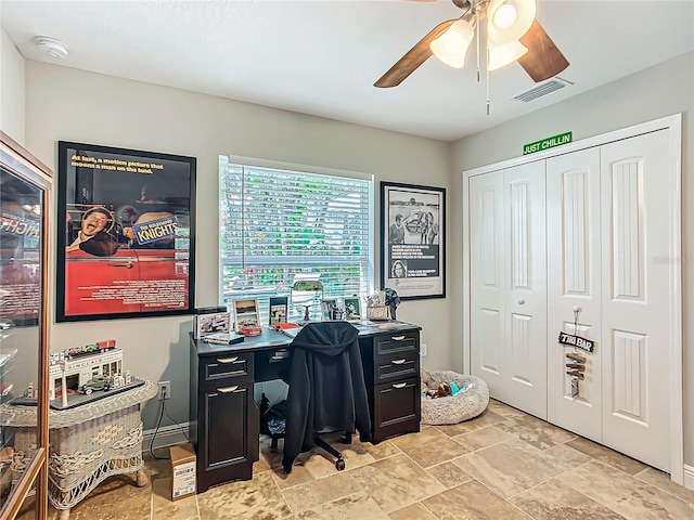 office area featuring baseboards, stone finish floor, visible vents, and a ceiling fan