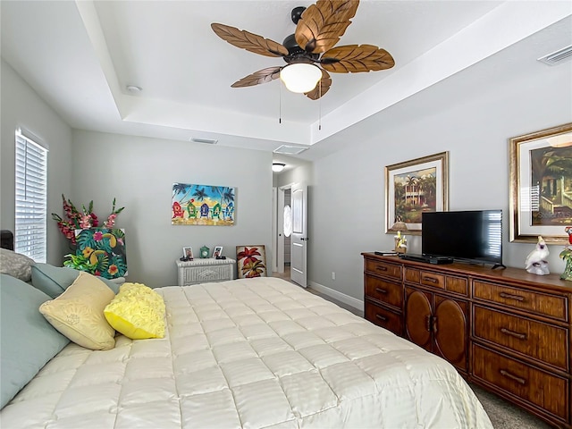 bedroom with a raised ceiling, visible vents, and baseboards