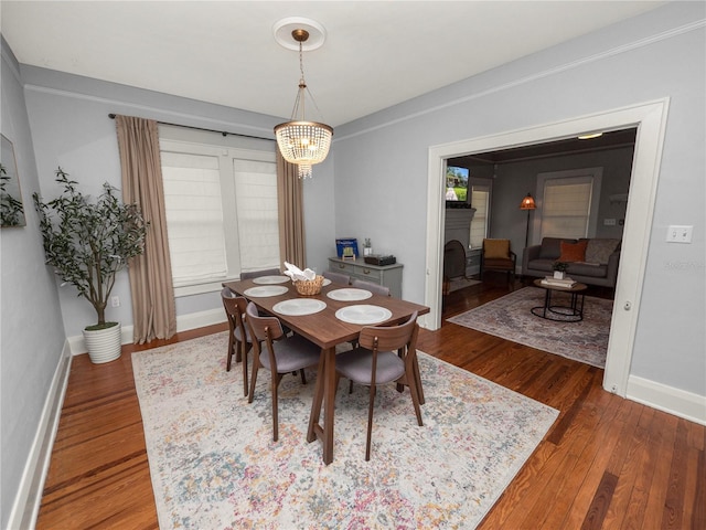 dining room with an inviting chandelier, a fireplace, baseboards, and wood finished floors