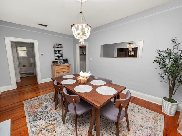 dining area with an inviting chandelier, baseboards, and wood finished floors