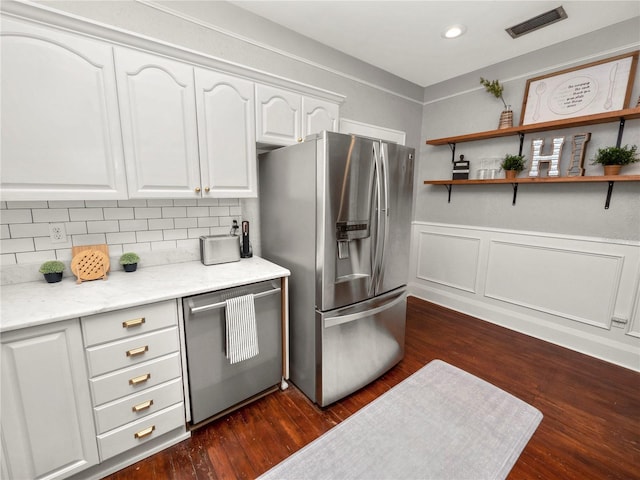 kitchen featuring a wainscoted wall, dark wood-style flooring, visible vents, white cabinetry, and appliances with stainless steel finishes