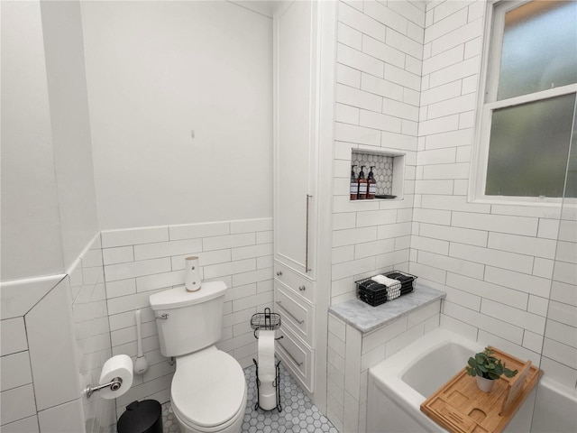 bathroom with a tub to relax in, tile walls, and toilet