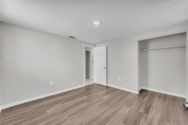 unfurnished bedroom with a closet, visible vents, baseboards, and wood finished floors