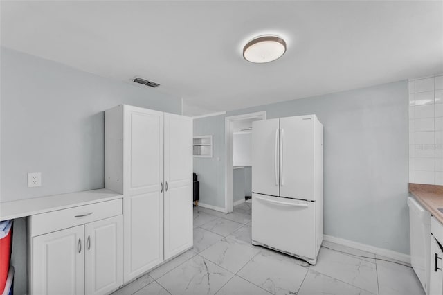 kitchen featuring marble finish floor, white cabinetry, visible vents, and freestanding refrigerator