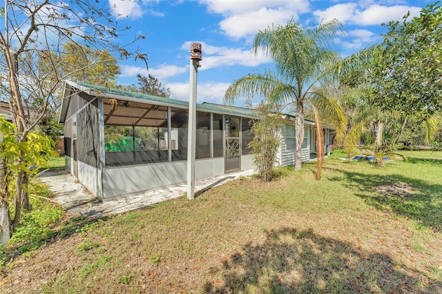 back of property with a sunroom and a yard