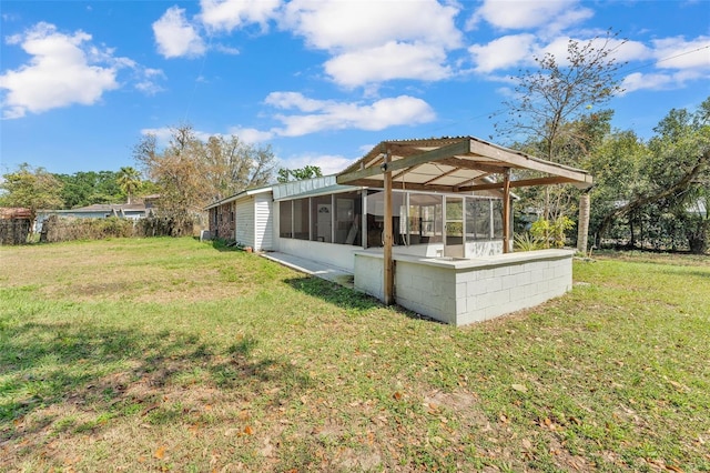 back of property featuring a sunroom and a lawn