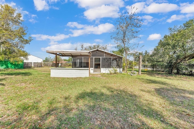 rear view of property with a yard, a carport, fence, and a sunroom