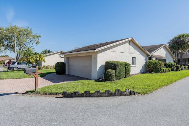 view of home's exterior featuring a garage, a yard, decorative driveway, and stucco siding