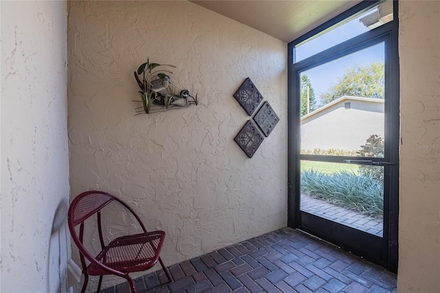 doorway to outside with brick floor and a textured wall