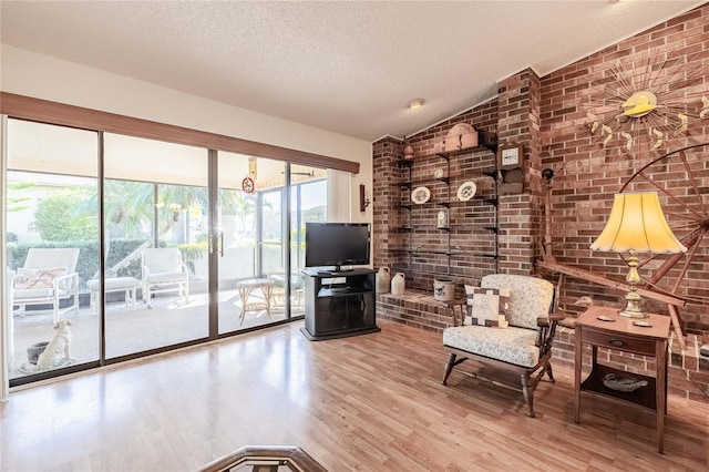 unfurnished room with a textured ceiling, vaulted ceiling, and wood finished floors