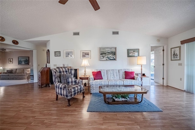 living area with vaulted ceiling, wood finished floors, visible vents, and a ceiling fan