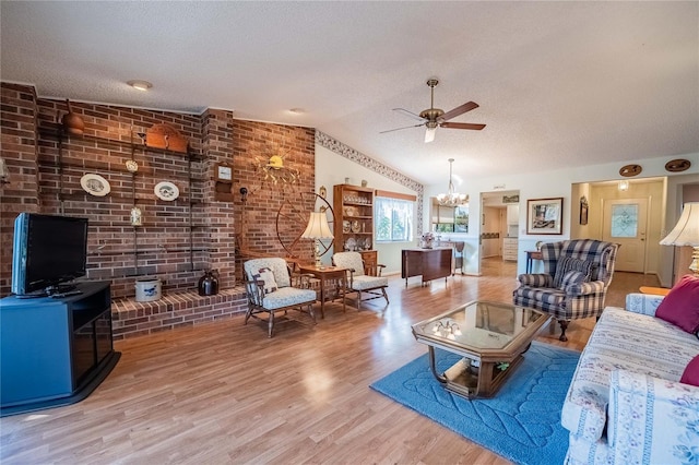 living area with ceiling fan with notable chandelier, lofted ceiling, a textured ceiling, and wood finished floors