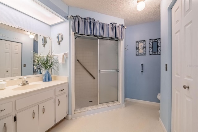 full bath with a stall shower, baseboards, toilet, a textured ceiling, and vanity