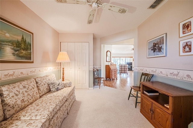 living room with visible vents, light carpet, and a ceiling fan