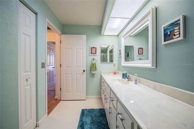 bathroom featuring vanity, baseboards, and a textured ceiling