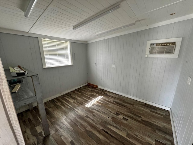 spare room featuring an AC wall unit, wood finished floors, and baseboards