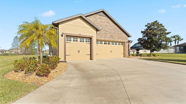 view of side of home featuring a yard, stucco siding, a garage, stone siding, and driveway