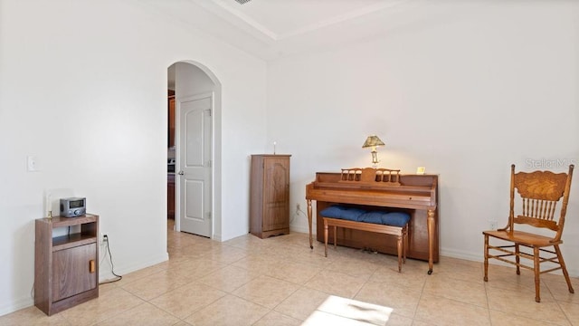 sitting room featuring arched walkways, baseboards, and light tile patterned floors