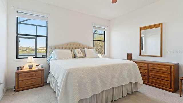 bedroom with a ceiling fan, light carpet, and multiple windows