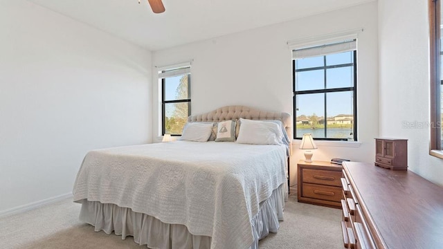 bedroom with light carpet, multiple windows, and baseboards