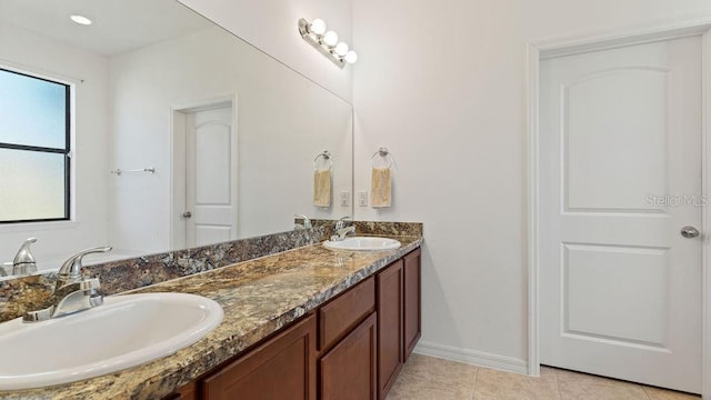 bathroom featuring double vanity, baseboards, a sink, and tile patterned floors