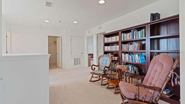 living area featuring recessed lighting, visible vents, light carpet, and a textured ceiling