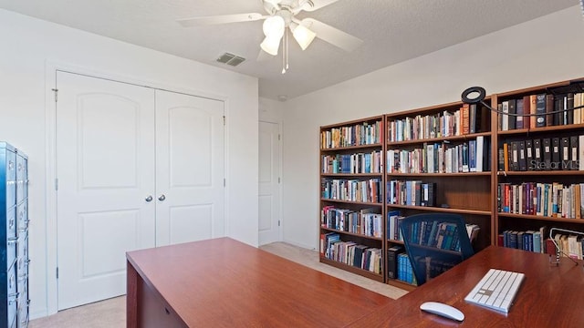 carpeted home office featuring a ceiling fan, visible vents, and a textured ceiling