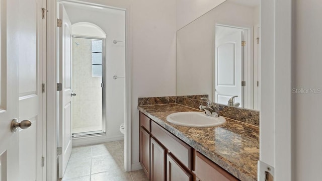 bathroom featuring toilet, a shower stall, vanity, and tile patterned floors