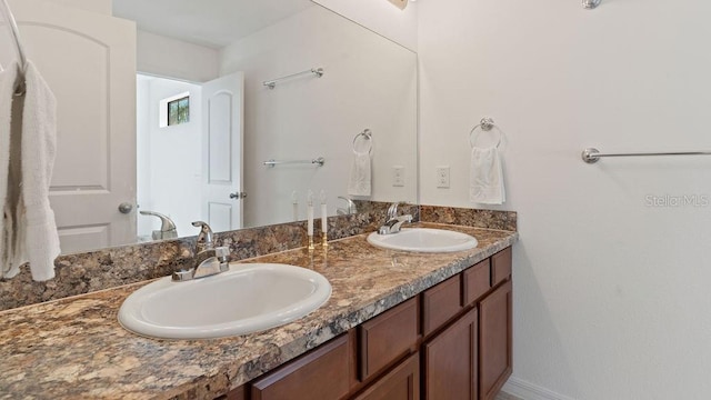 full bath with a sink, baseboards, and double vanity