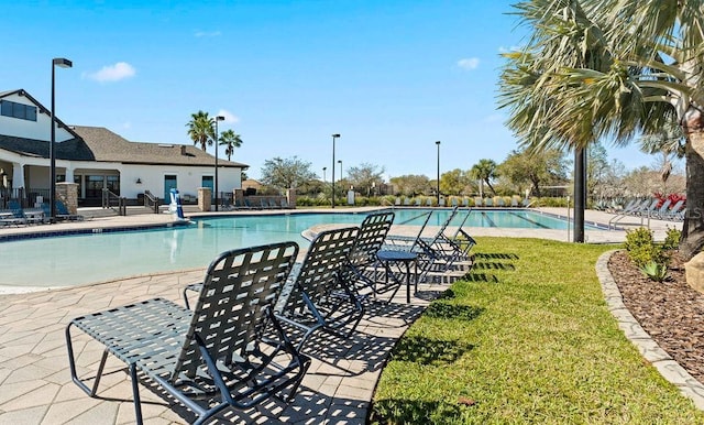 community pool featuring a patio area, a lawn, and fence