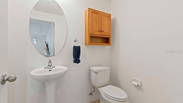 half bathroom featuring baseboards and toilet