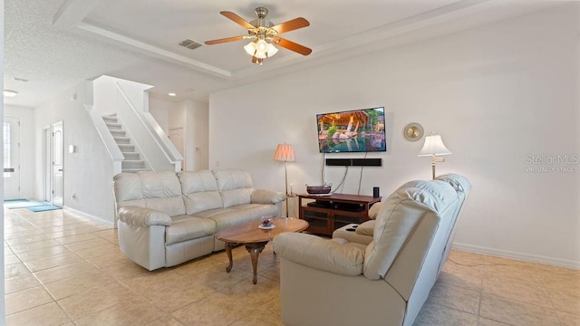 living room with light tile patterned flooring, visible vents, baseboards, stairs, and a tray ceiling