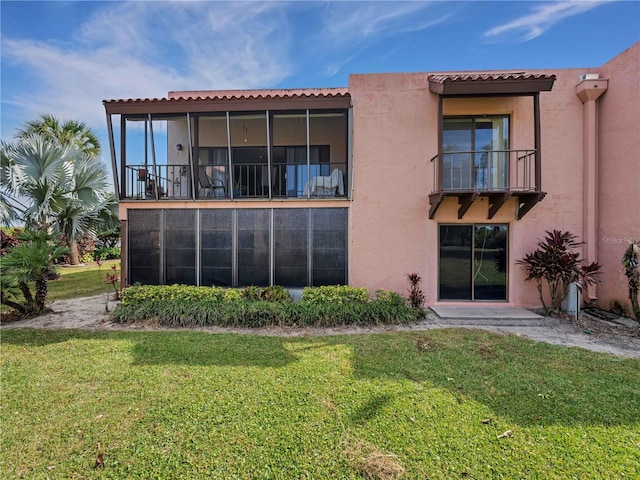 rear view of property featuring stucco siding and a yard