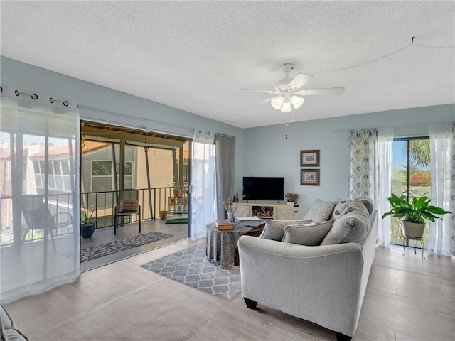 living area featuring a wealth of natural light, a textured ceiling, and ceiling fan