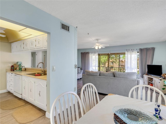 dining space featuring a textured ceiling, visible vents, light wood finished floors, and ceiling fan