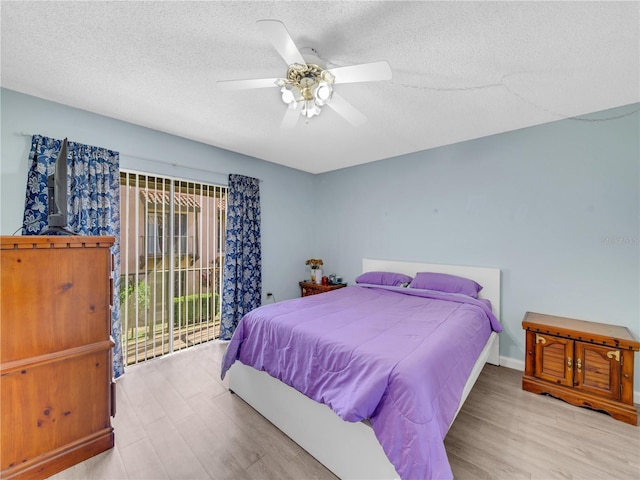 bedroom with ceiling fan, wood finished floors, a textured ceiling, and access to exterior