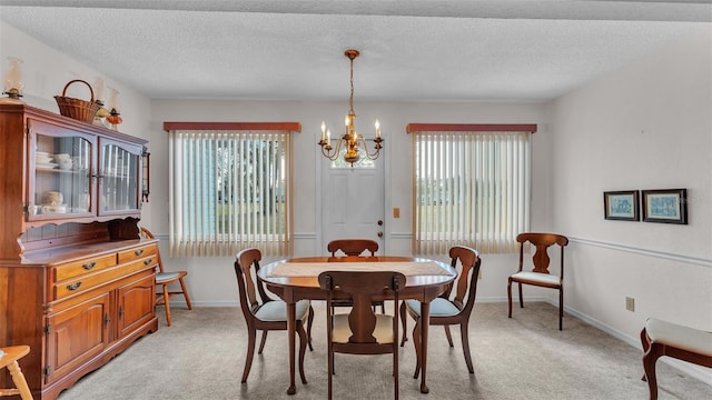 dining space with light carpet, a healthy amount of sunlight, a chandelier, and a textured ceiling