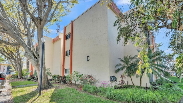 view of side of property featuring a lawn and stucco siding