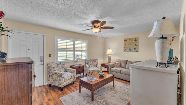 living area featuring ceiling fan, a textured ceiling, and wood finished floors