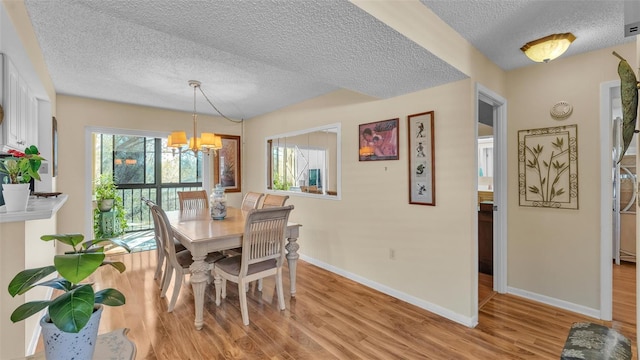 dining space featuring light wood-style floors, baseboards, and a notable chandelier