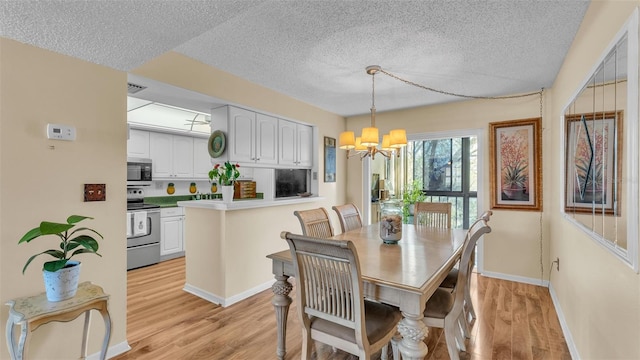 dining area with a notable chandelier, visible vents, light wood-style flooring, a textured ceiling, and baseboards