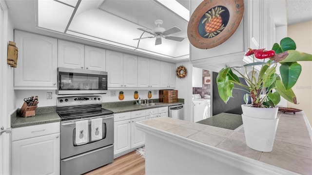 kitchen with appliances with stainless steel finishes, white cabinets, and washing machine and clothes dryer