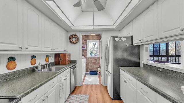 kitchen with a tray ceiling, dark countertops, appliances with stainless steel finishes, and white cabinetry