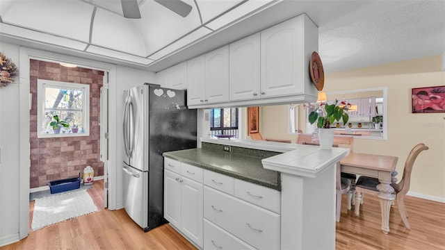 kitchen with plenty of natural light, light wood-type flooring, freestanding refrigerator, and white cabinetry