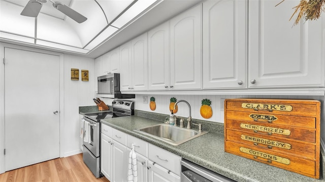 kitchen featuring appliances with stainless steel finishes, light wood-type flooring, white cabinets, and a sink