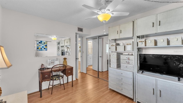 interior space with light wood-style flooring, visible vents, ceiling fan, and a textured ceiling