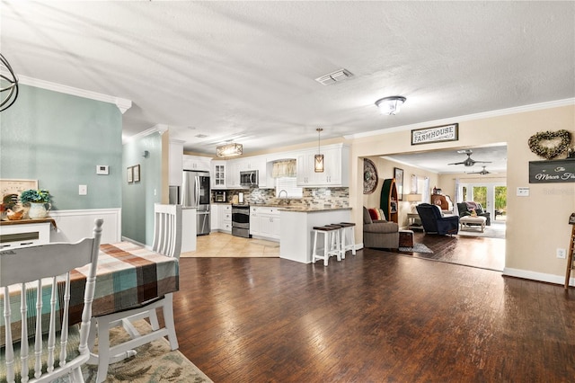 living room with french doors, crown molding, light wood finished floors, visible vents, and a textured ceiling