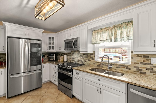 kitchen featuring stainless steel appliances, white cabinets, light tile patterned flooring, and a sink